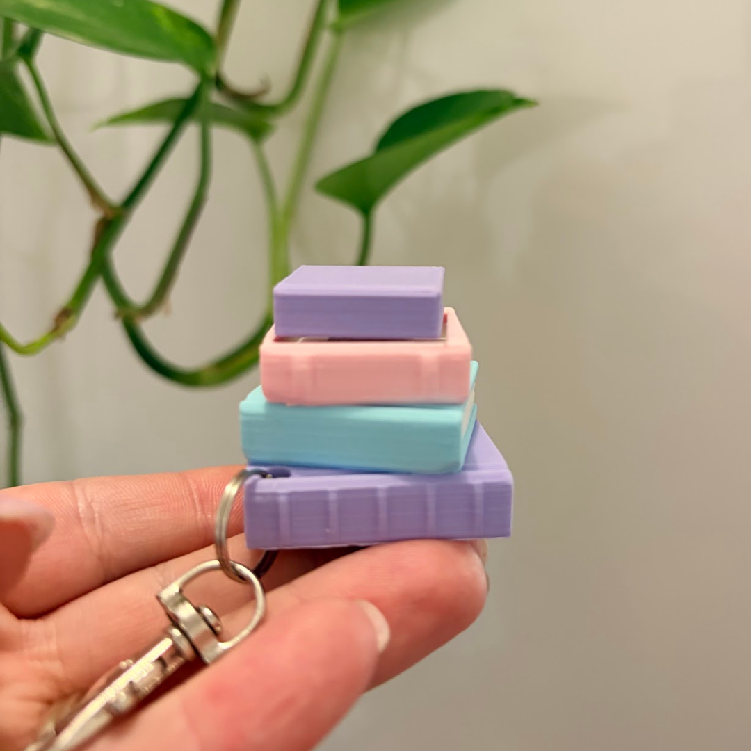 Stack of colorful square erasers on a keychain held by a hand with a plant in the background
