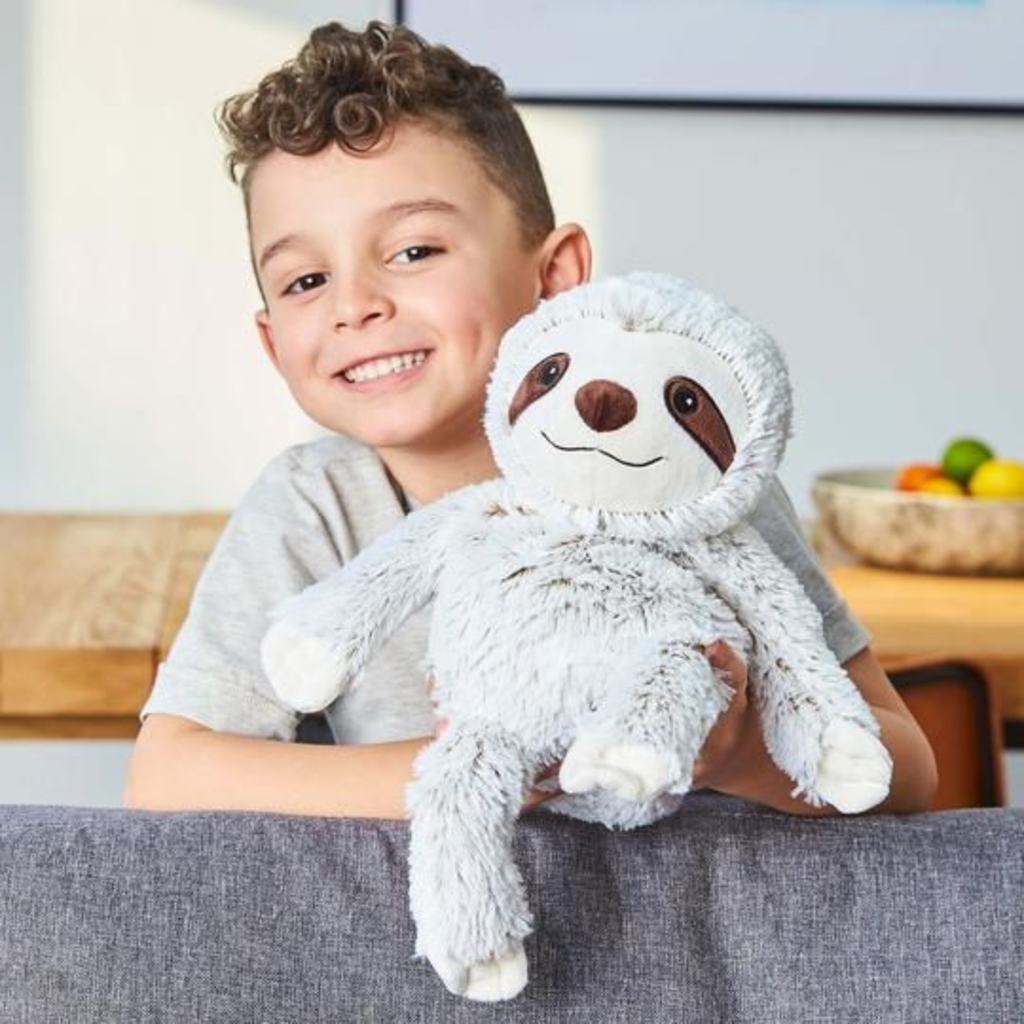Child holding a plush sloth toy in a home setting