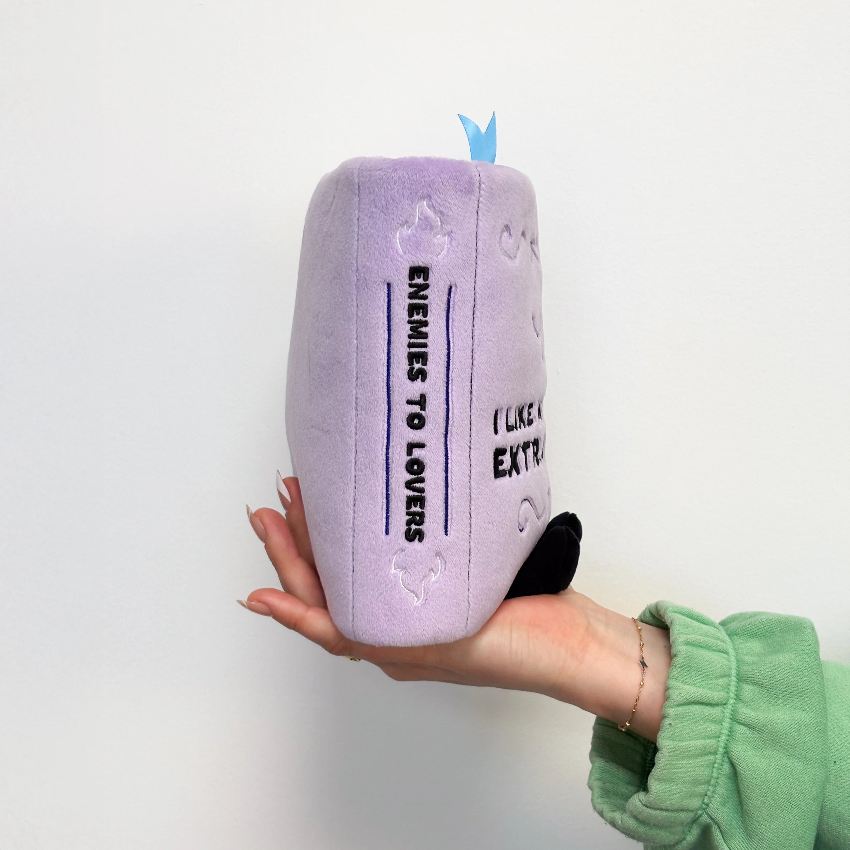 Purple plush pillow with text held by a person against a white background