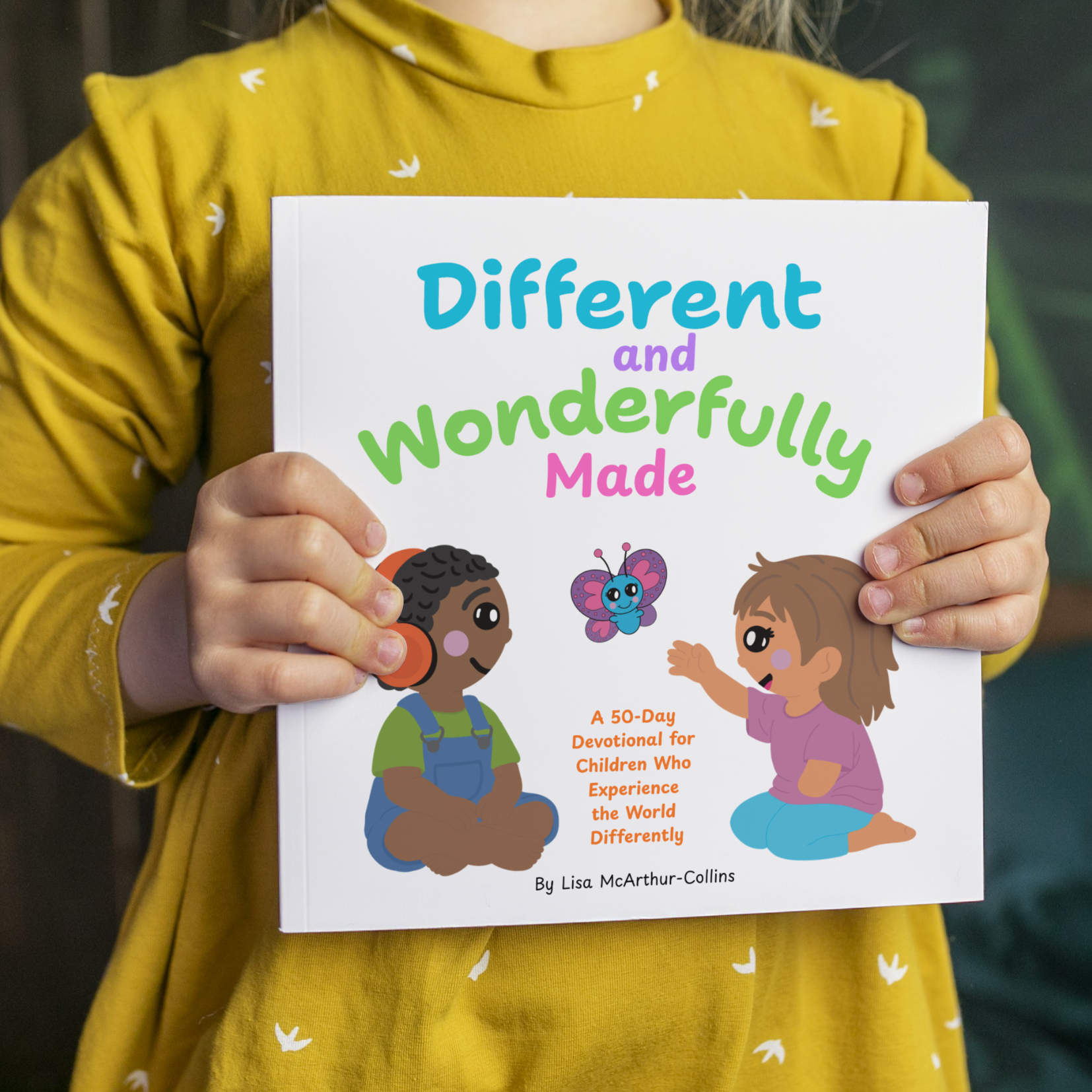 Person holding a book titled 'Different and Wonderfully Made' with illustrations on the cover.